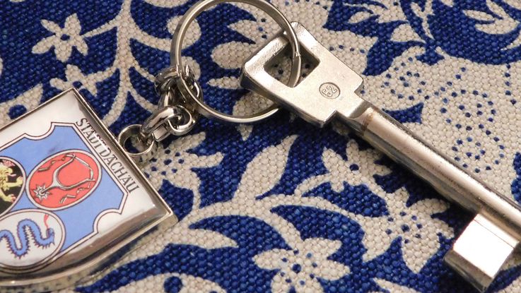 Foto von Schlüssel mit Dachauer Wappen Schlüsselanhänger auf blau weißer Tischdecke, Symbobild für die Übernachtungsmöglichkeit im Münchner UmlandFoto: P. Töpperwien